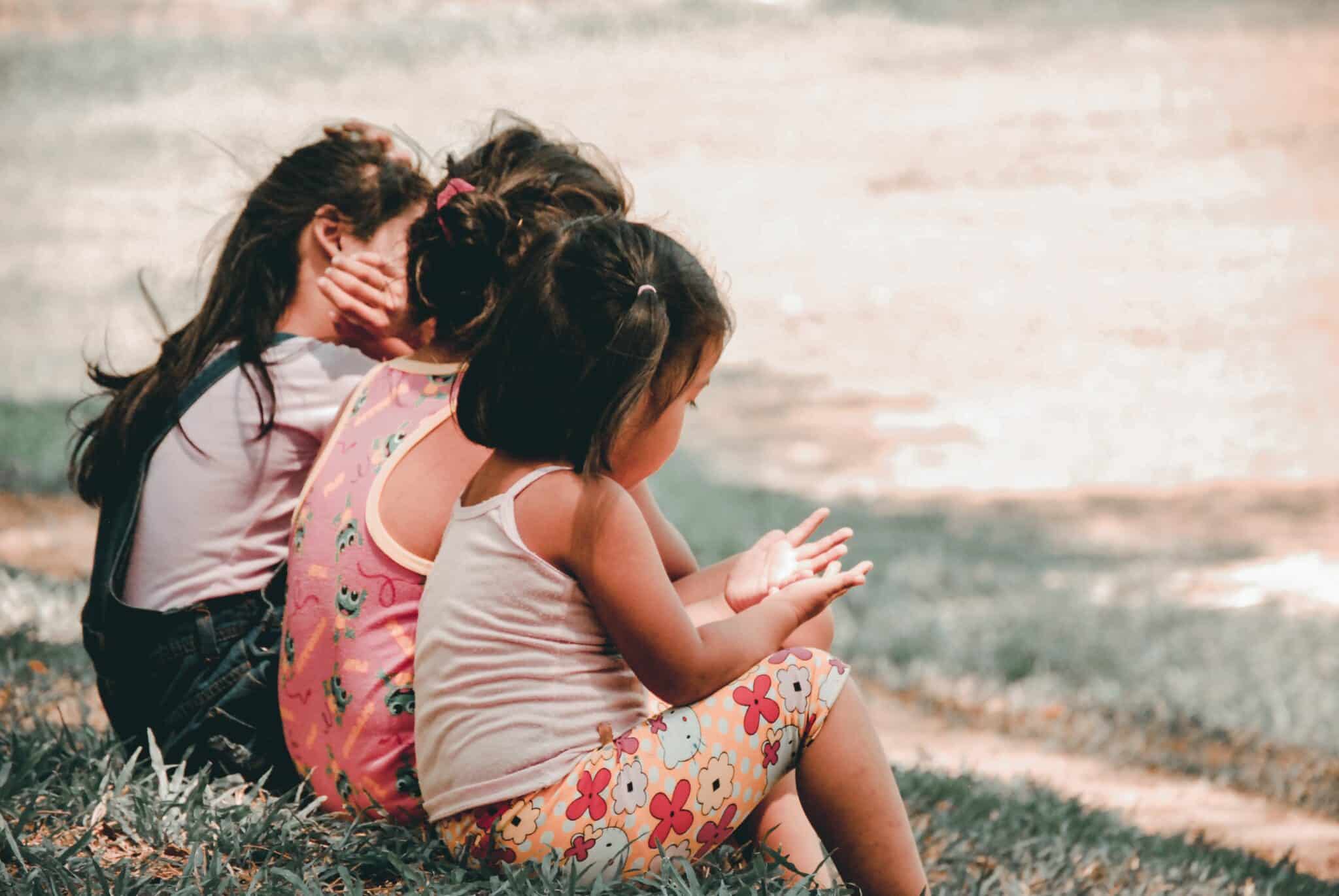 three young children sat on the grass playing