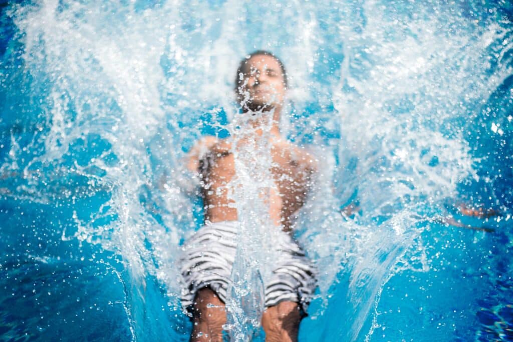 young man diving backwards in to a swimming pool