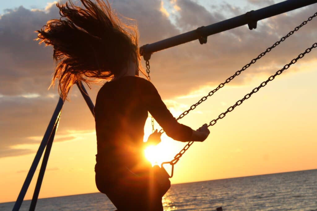 a young girl with long hair on a beach swing