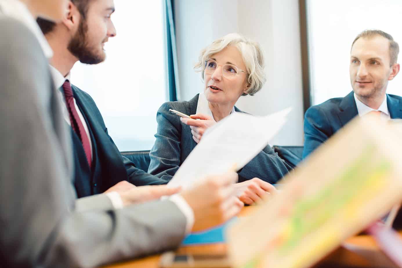 an older businesswoman directing a meeting of peers