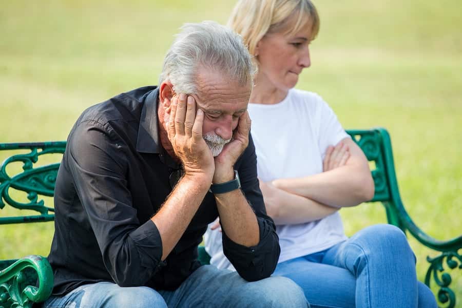 senior couple having relationship problems while sat on a park bench