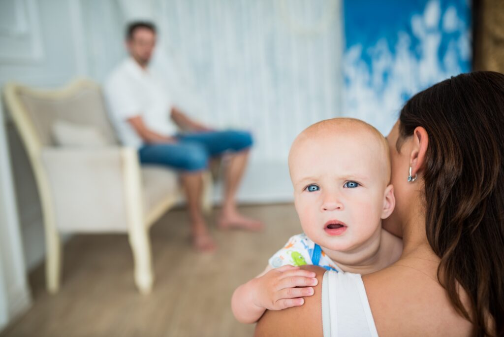 baby with bright blue eyes being comforted by his mother