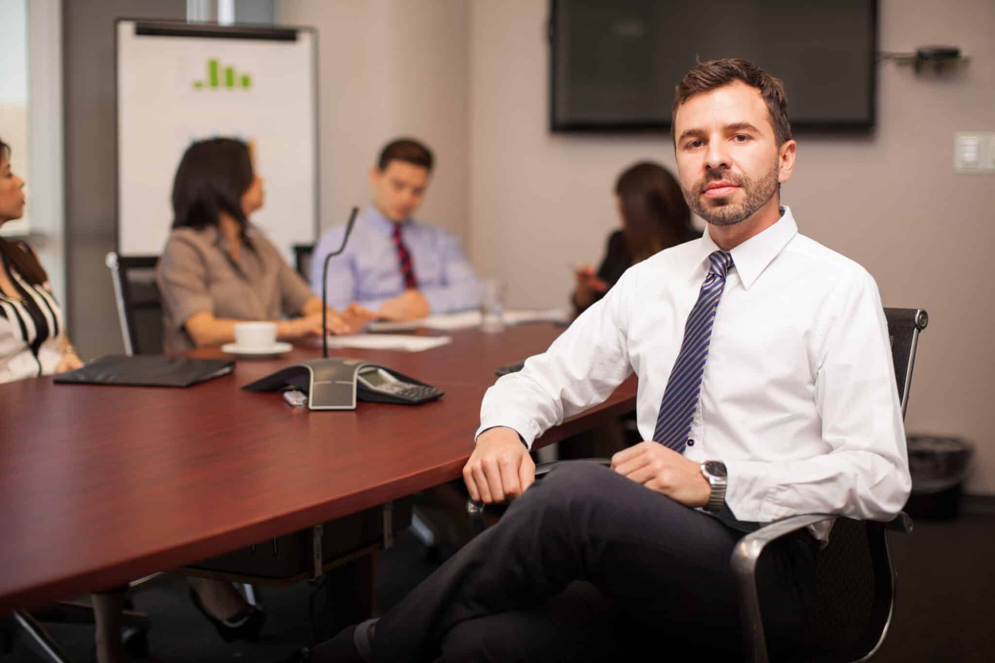 Confident young businessman sitting in a conference room with some clients