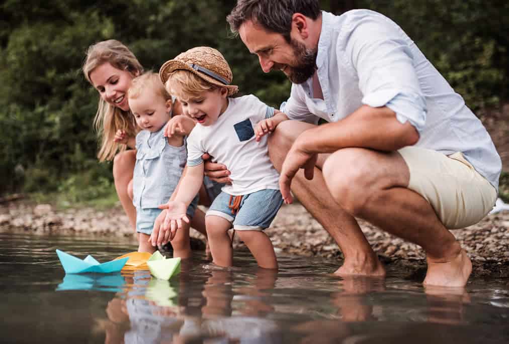 happy family with origami boats in shallow water