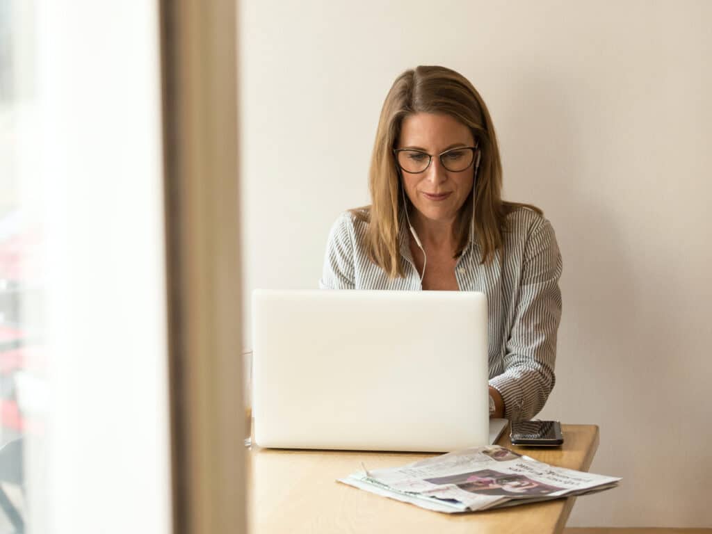 woman with glasses and ear phones in front of computer