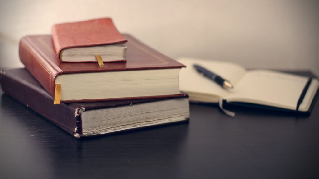 stack of books with notepad and pen