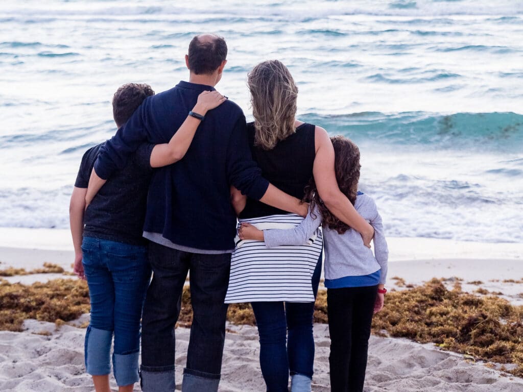 an established family embracing while looking out over the ocean