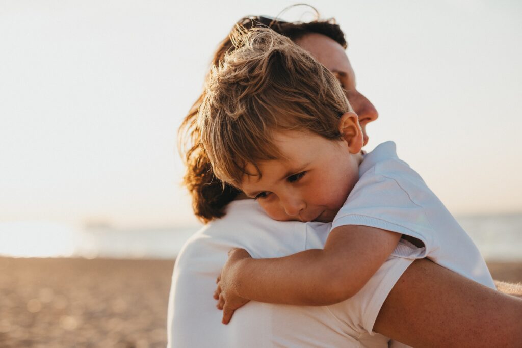 a mother hugging her son on the beach