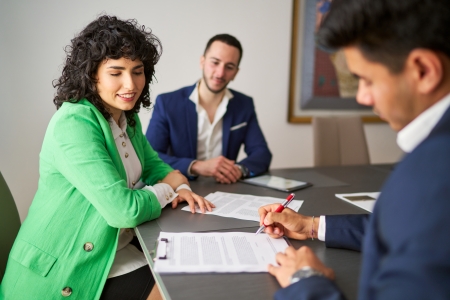 Businessman signing contract with smiling businesswoman observing