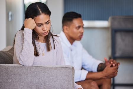 Sad, woman and couple in unhappy marriage from argument, fight or disagreement on living room sofa